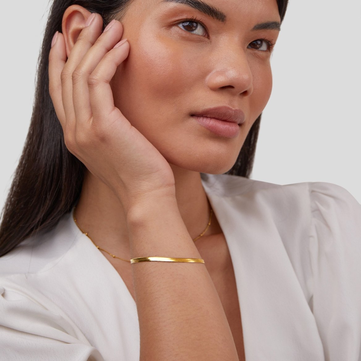 Sarya Snake Chain Gold Bracelet, worn on a wrist with a hand resting near the face, gold chain