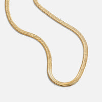 Sarya Snake Chain Gold Necklace, gold snake chain lying in a curving loop on white