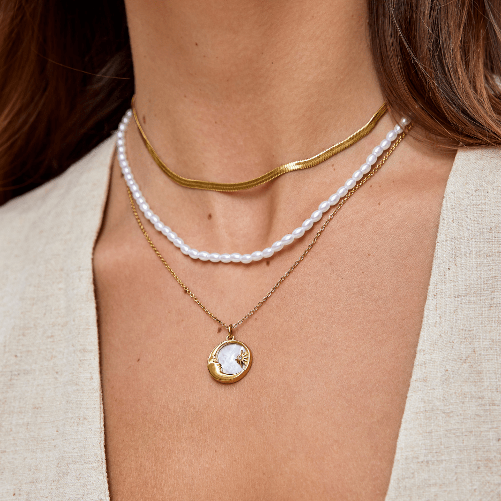 Sarya Snake Chain Gold Necklace, worn layered on a neck with pearls and a gold coin pendant