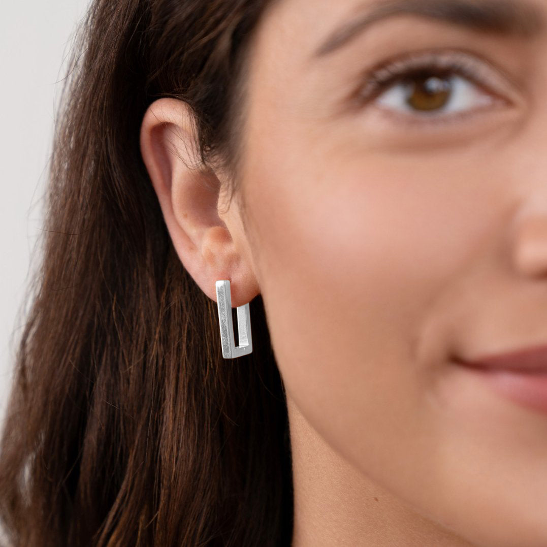 Silver Rectangle Hoop Earrings, worn on an ear, matte silver rectangular hoop
