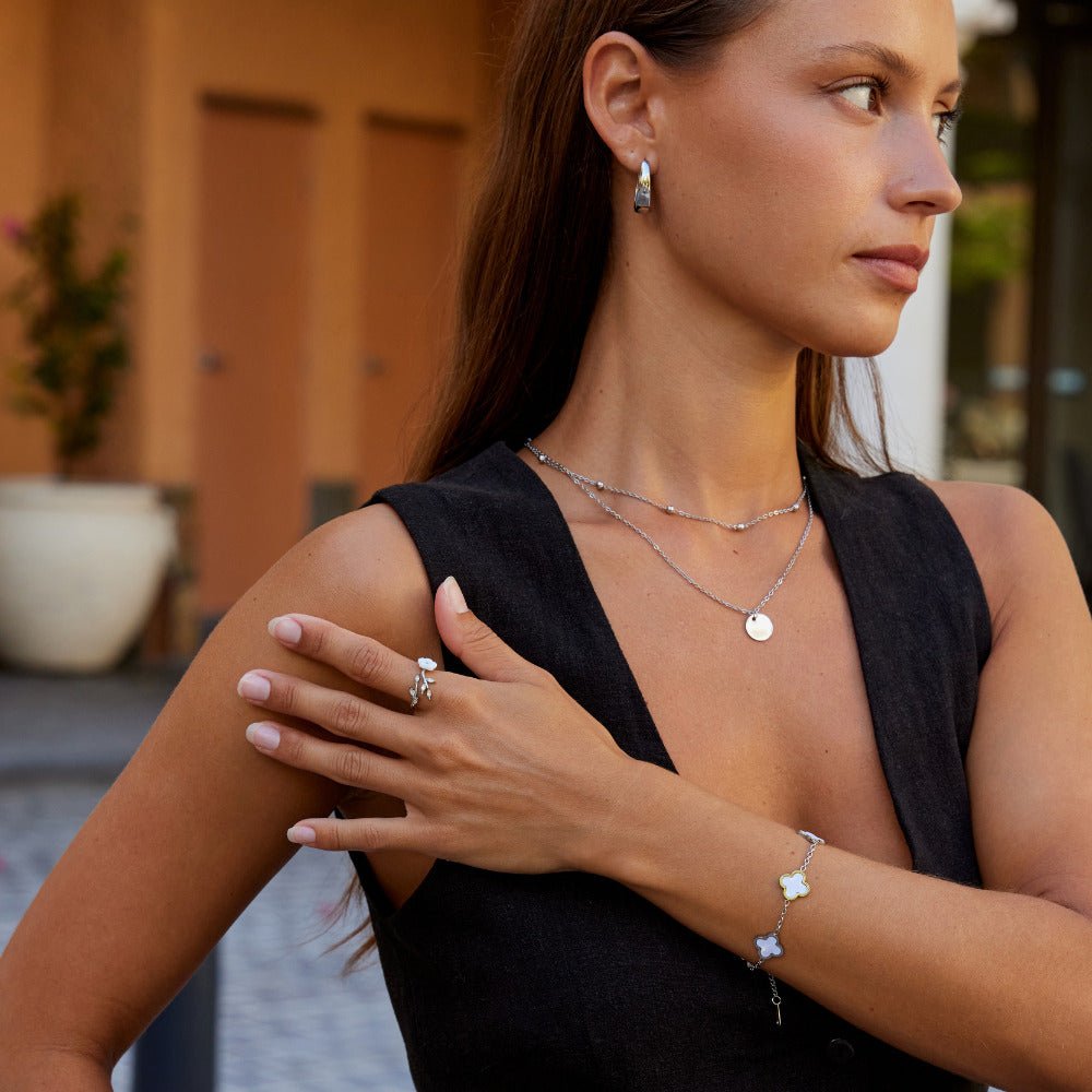 Silver White Blossom Flower Ring, worn on a hand with a layered necklace and clover bracelet