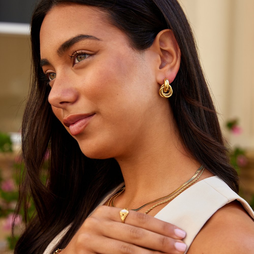 Sofia Twisted Gold Hoop Earrings, worn on a model with layered gold necklaces and a gold ring