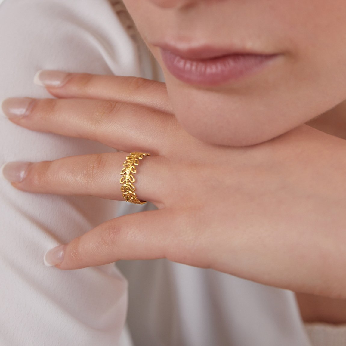 Summer Bloom Leaf Ring, worn on a hand against a white top, close-up on a gold leaf-textured band