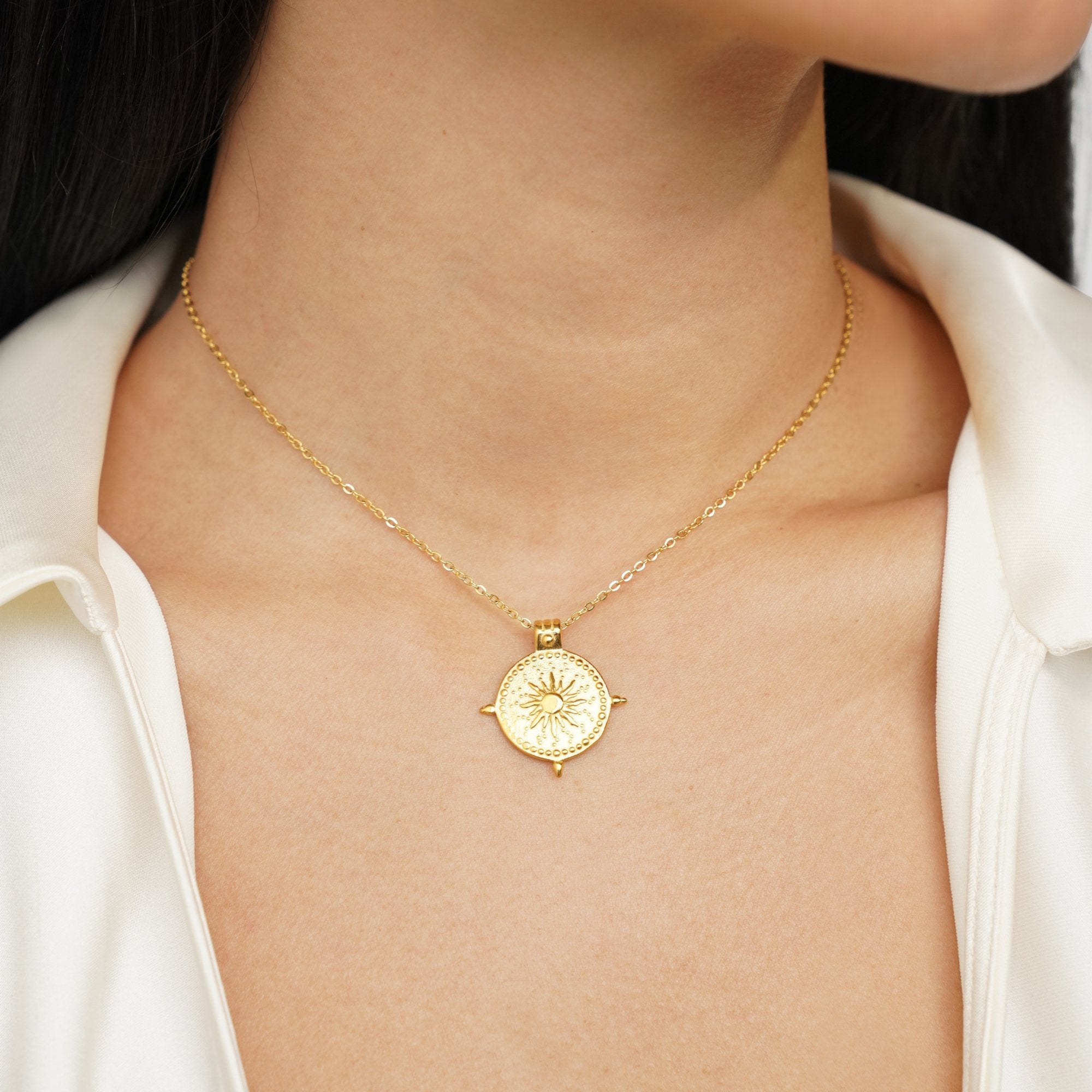 Summer Solstice Gold Necklace, worn at the neck over a white satin shirt, gold sunburst disc pendant