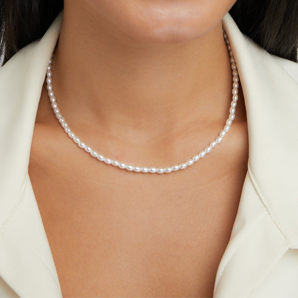 Temi Pearl Necklace, worn on a neck with a cream open-collar blouse, white oval beads