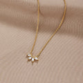 Tiffany Crystal Leaf Pendant Necklace, laid flat on beige fabric, gold chain with five pointed