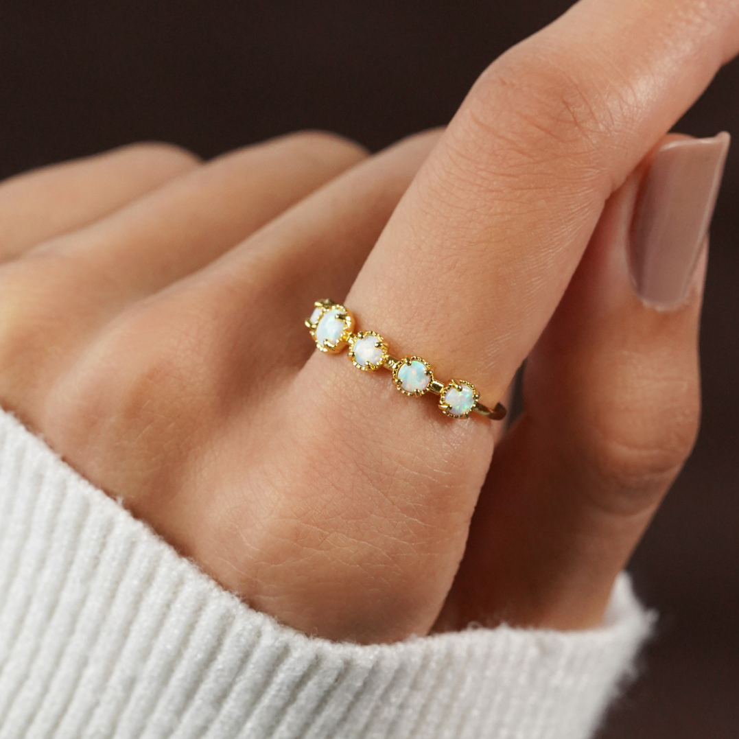 Tiffany Opal Stone Ring, worn on a hand over a white knit sleeve, gold band with opals
