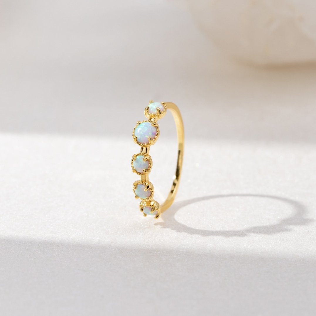 Tiffany Opal Stone Ring, standing upright on white marble, gold band with five opals