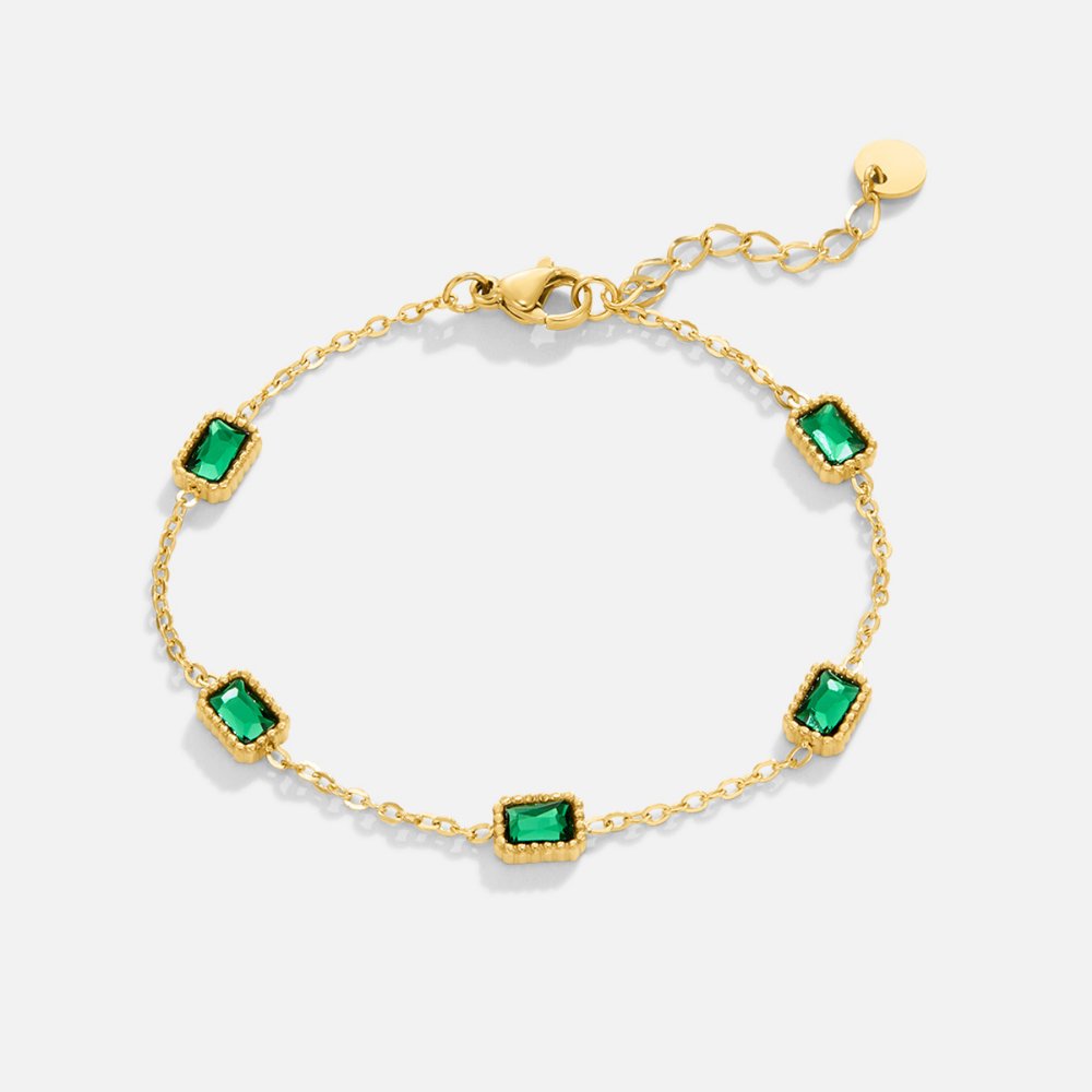 Trinity Emerald Bracelet, flat lay of gold chain bracelet with five green emerald-cut stones