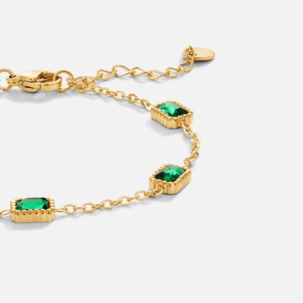 Trinity Emerald Bracelet, close-up of gold chain bracelet with green emerald-cut stones on white