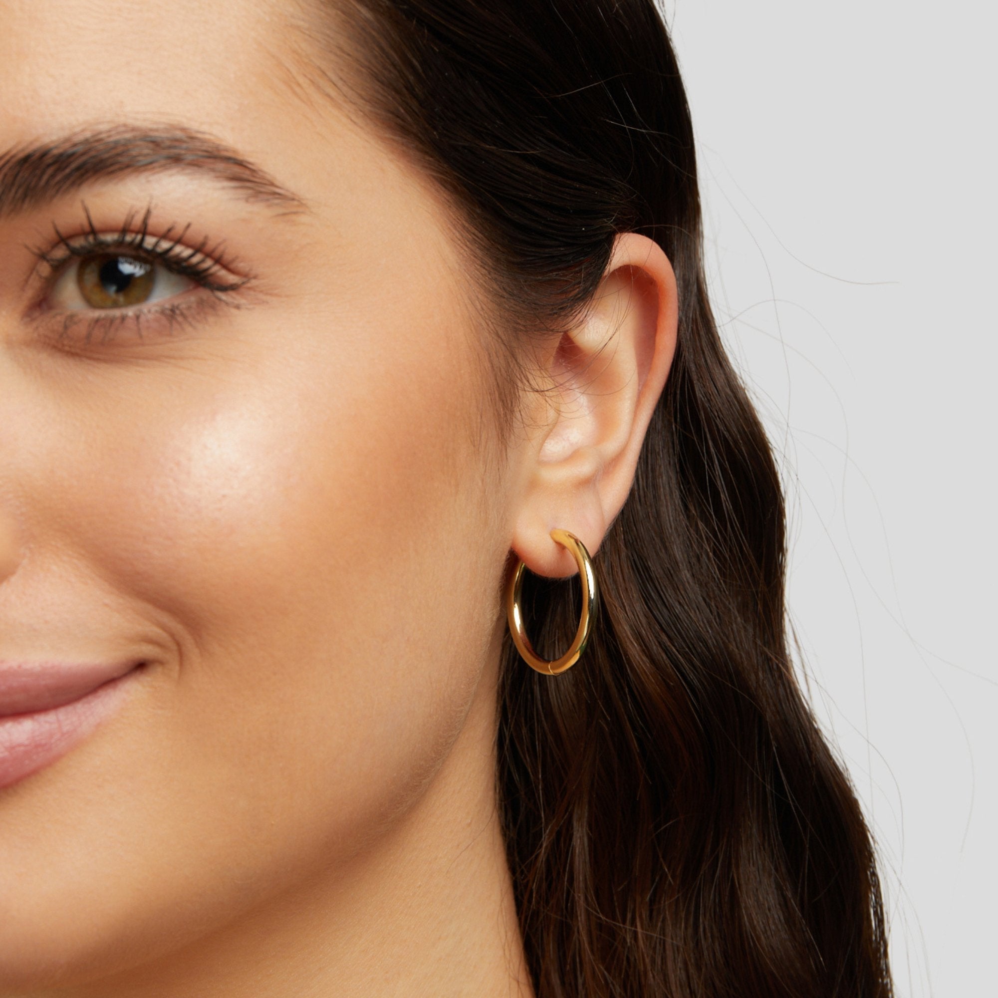 Triple Hoop Earrings Set, worn on an ear, close-up of a smooth gold hoop