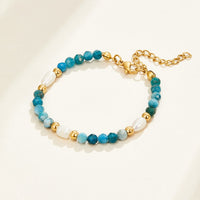 Turquoise Blue & Pearl Bead Bracelet, laid flat on a cream surface, blue beads with pearls and