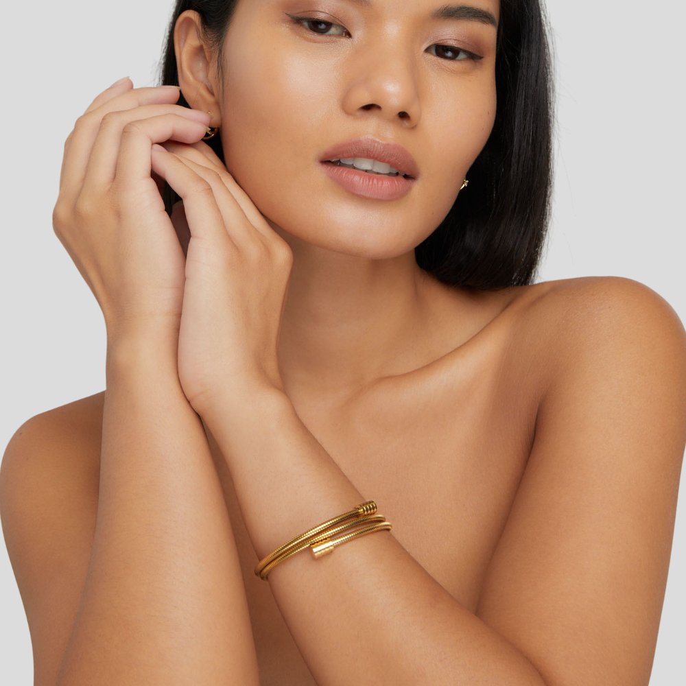 Twisted Gold Bracelet, worn on a wrist with hands raised near the face