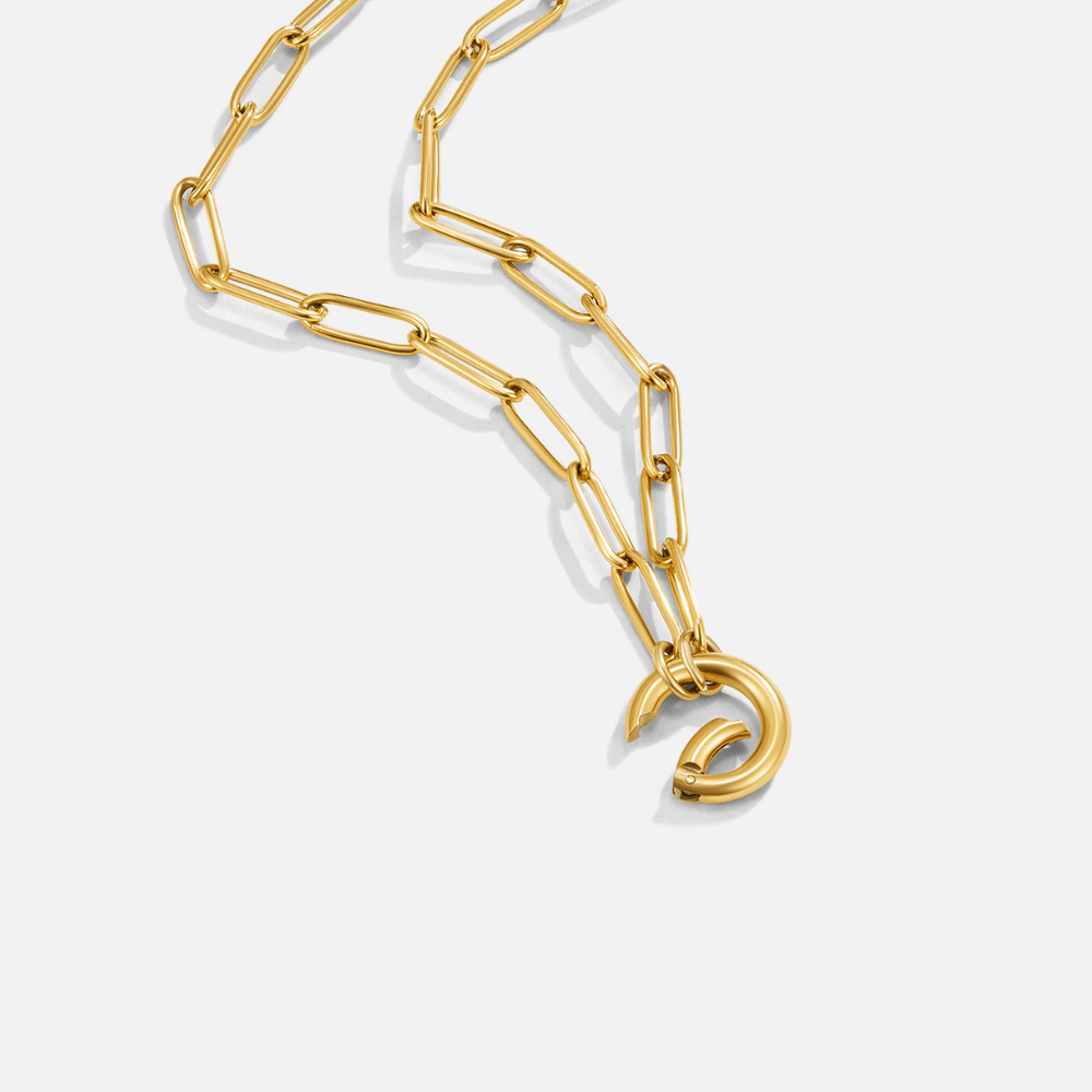 Via Gold Chain Necklace, gold paperclip chain laid out on white with a round clasp hanging