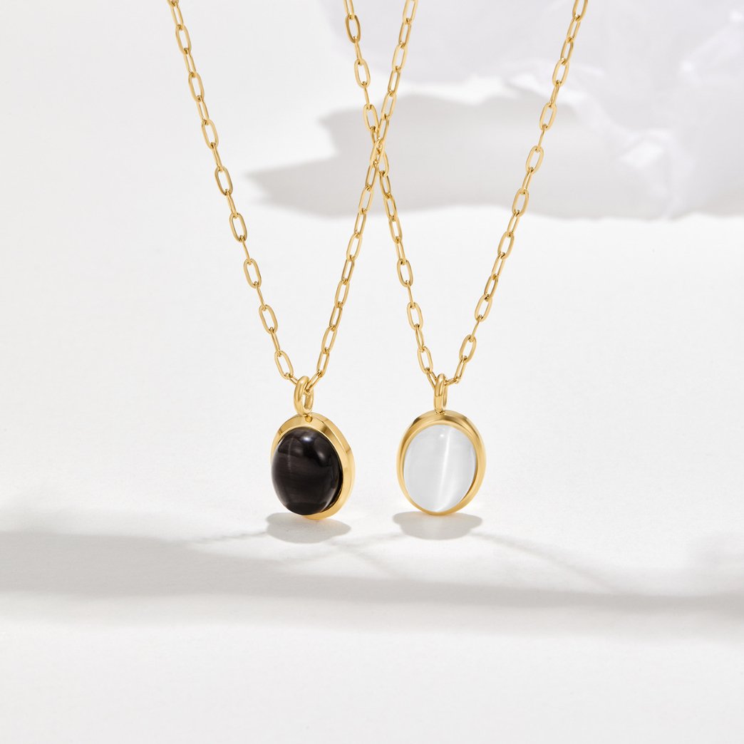 White Opal Necklace, two gold chain necklaces with oval pendants, one black and one white, on