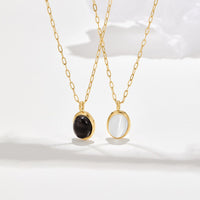 White Opal Necklace, two gold chain necklaces with oval pendants, one black and one white, on