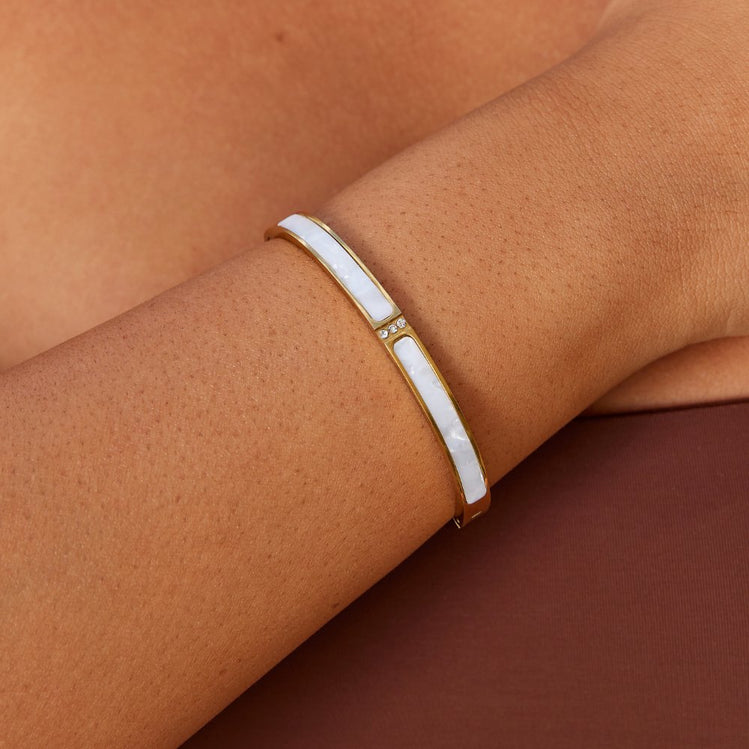 White Sahara Gold Bangle, worn on a wrist, white mother-of-pearl panels and small crystal accent