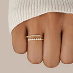“Wrap Me” Pearl & Crystal Ring, worn on a finger in a cream knit sleeve, gold with pearls and stones